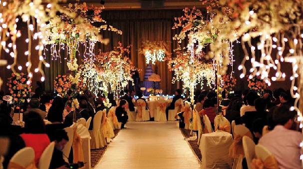 Wedding celebrations at a party hall, guests enjoying the lavish arrangements and decorations.