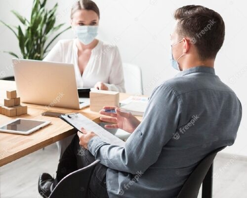 An image of 2 employee working with a mask on their face
